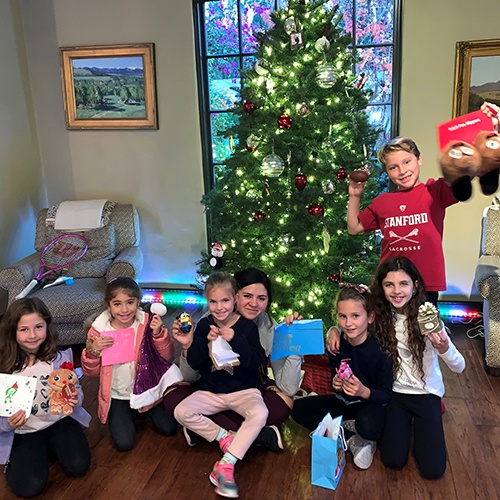 Six kids ad their grown-up friend Jody posing with their Christmas Market creations in front of a Christmas tree